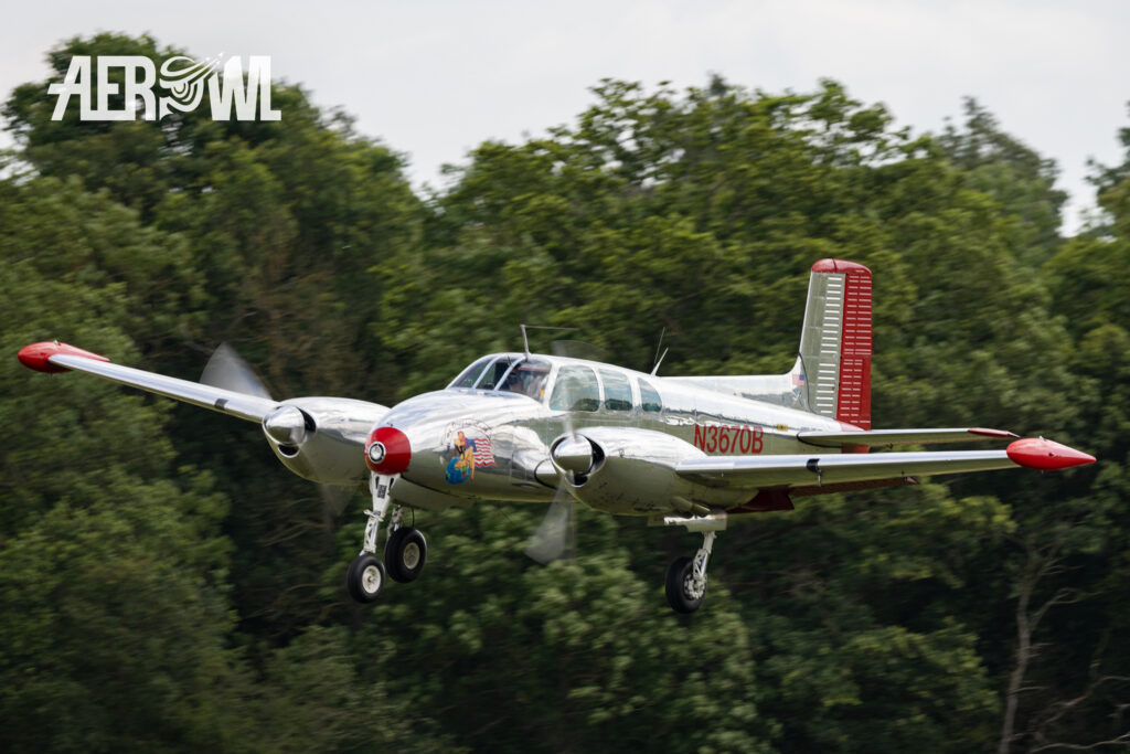 The chrome and red shining Beechcraft Model 50 Twin Bonanza approachs during the Stearman&Friends2023 over the Bienenfarm near Berlin, Germany.