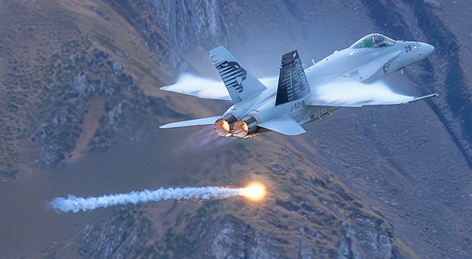 A Swiss Air Force Boeing F/A-18C Hornet passes by and drops flares during the Axalp Air Shoot 2023 in the Swiss Alps.
