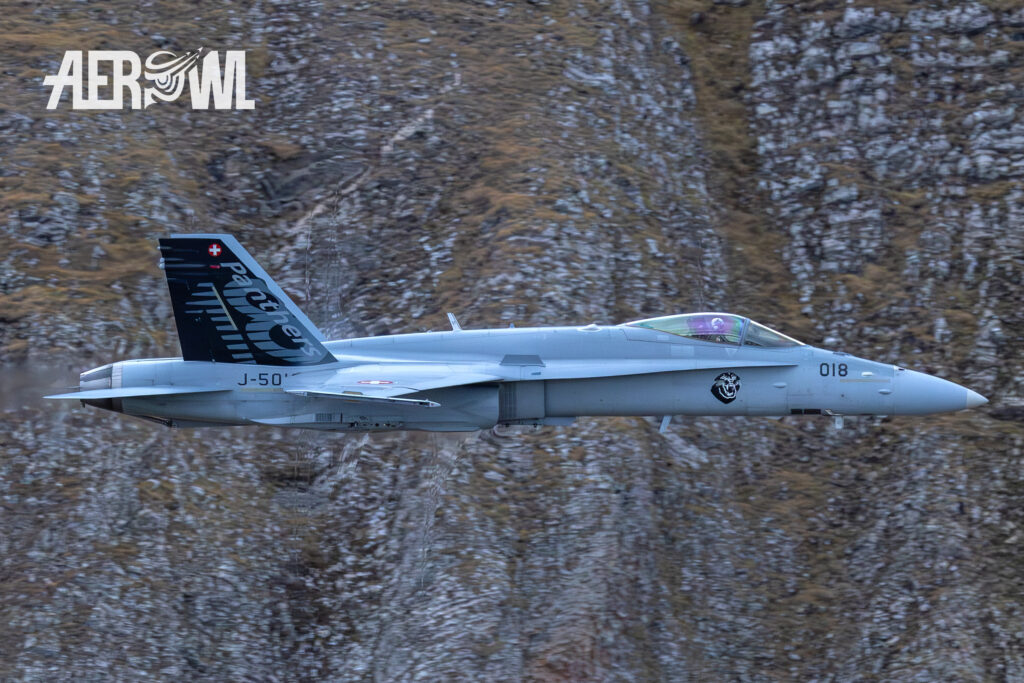 A super-fast Boeing F/A-18C Hornet of the Swiss Air Force passes by at 1000 km/h during the Axalp Air Shoot 2023 in the Swiss Alps. You can clearly see the "Mach cones" near the fuselage of the Hornet.