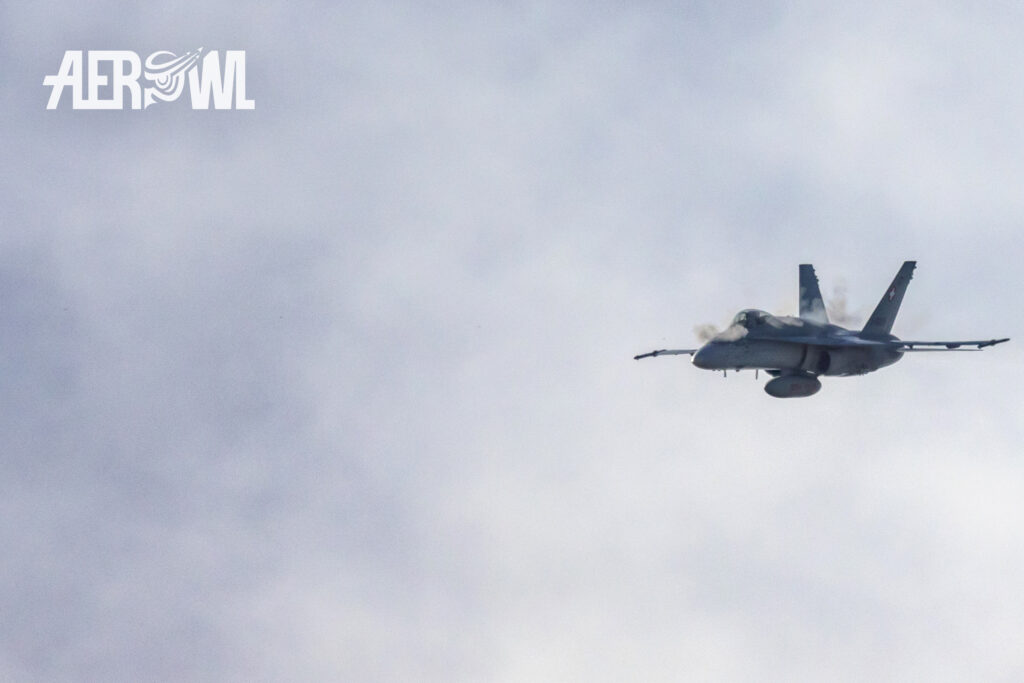 A Boeing F/A-18C Hornet of the Swiss Air Force fires its 20mm cannon during the Axalp 2022 training in the Swiss mountains. The 20 mm bullets are visible.