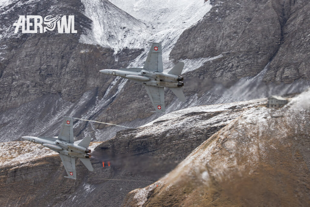 Two Boeing F/A-18C Hornet of the Swiss Air Force during a hard turn during the Axalp 2023 with afterburners in the Swiss Alps.