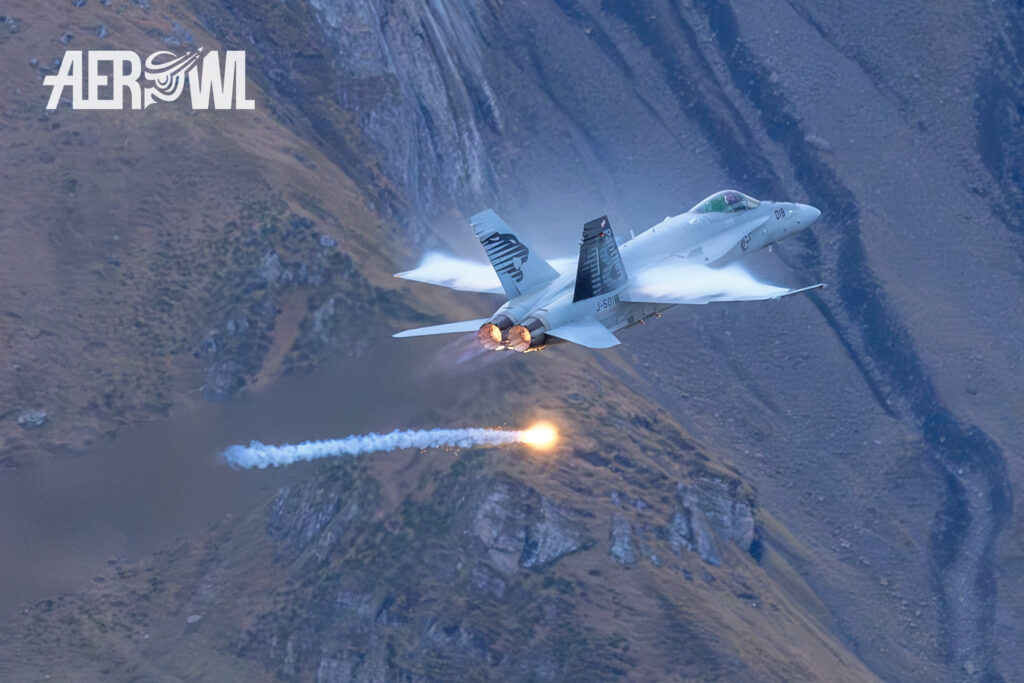 A Swiss Air Force Boeing F/A-18C Hornet passes by and drops flares during the Axalp Air Shoot 2023 in the Swiss Alps.